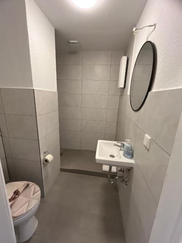 a bathroom with a sink and a toilet and a mirror at Zentrale Unterkunft in Neumünster in Neumünster