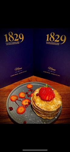 a pancake with a strawberry on a plate on a table at Thomas Arms Hotel in Llanelli