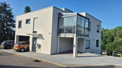 a white house with a balcony on the side of it at Apartments Seibel Doppel-Zweibettzimmer mit Küche und Wintergarten in Reutlingen
