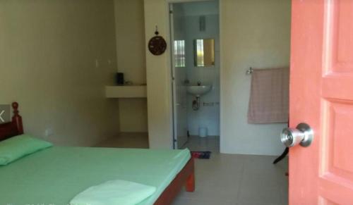 a room with a bed and a bathroom with a sink at Anton's Beach Resort in Oslob