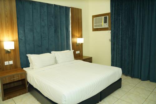 a bedroom with a large white bed with blue curtains at شقق رايف الزهور in Dammam