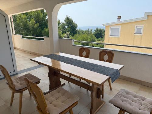 a balcony with a wooden table and chairs on a balcony at Apartman Kraljević Vir 2 in Vir