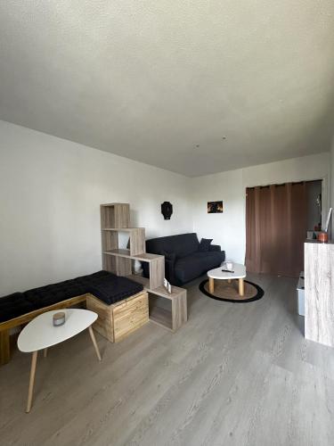 un salon avec un canapé bleu et des tables dans l'établissement Vacances a Biscarrosse entre lacs, ocean et confort, à Biscarrosse