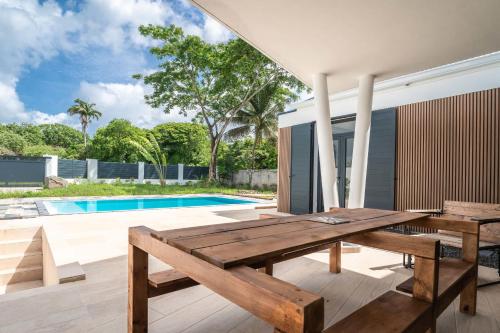 una mesa de picnic de madera en un patio junto a una piscina en Villa Kassav, en Port-Louis