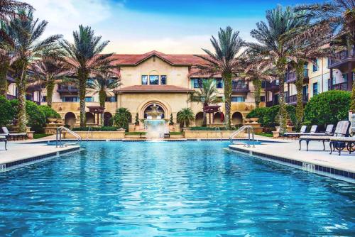 a pool in front of a building with palm trees at 1 BR Top Floor - private balcony & views 5304 in Saint Augustine