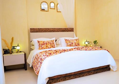 a bedroom with a bed with white sheets and orange pillows at Villa Sable de Mirleft Luxury Apartment in Mirleft