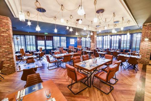 a restaurant with tables and chairs and windows at Holiday Inn Leeds Brighouse by IHG in Brighouse
