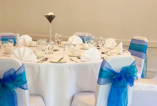 a table with chairs and a white table with blue bows at Holiday Inn Leeds Brighouse by IHG in Brighouse