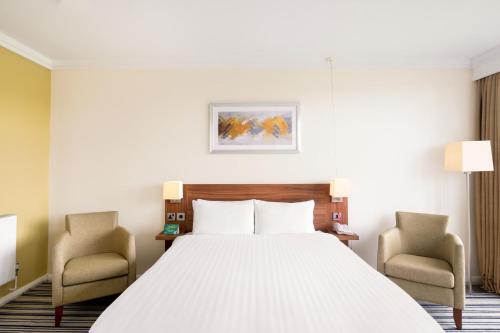 a hotel room with a bed and two chairs at Holiday Inn Leeds Brighouse by IHG in Brighouse