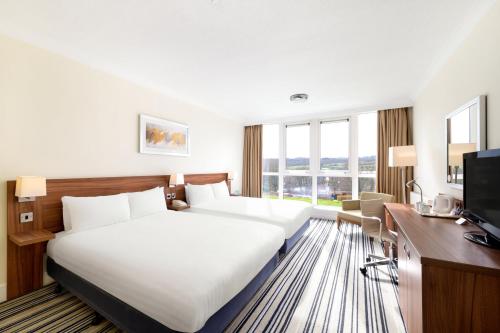 a hotel room with a bed and a desk and a television at Holiday Inn Leeds Brighouse by IHG in Brighouse