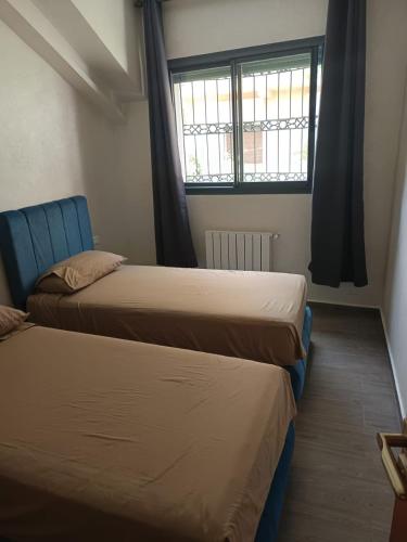 two beds in a room with a window at Le Refuge de Vittel 5 in Ifrane