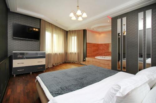 a bedroom with a bed and a television and a tub at 3х комнатная 2 спальни Арбат ЖК Столичный центр in Almaty