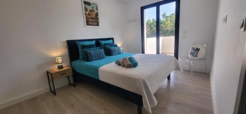 une chambre avec un grand lit avec des oreillers bleus dans l'établissement La Salanque Villa Standing Piscine chauffée, à Villelongue-de-la-Salanque