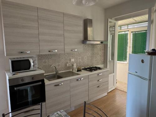 a kitchen with a refrigerator and a sink and a microwave at Appartamento Morelli Beach - Via Giacomelli 55 in Follonica