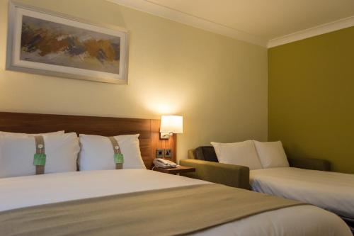 a hotel room with two beds and a couch at Holiday Inn Leeds Garforth by IHG in Garforth