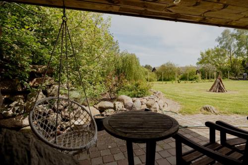 a patio with a table and a swing at Dandzenieki in Pāvilosta