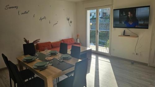 un salon avec une table à manger et une télévision dans l'établissement Maison hortensia, au Cheylard