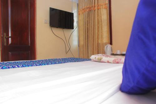 a bedroom with a bed with a tv on the wall at VTF Guest House in Accra