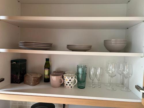 a shelf with wine glasses and plates and bottles at City Bloom Apartment in Kotka