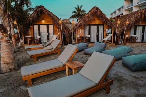 a row of chaise lounges and chairs on a beach at qema Mancora in Máncora