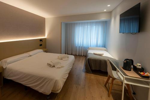 a room with two beds and a table and a window at EightRooms La Rioja Pension in Logroño