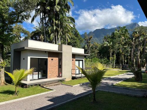 a small house in a park with palm trees at Vila do Porto Pousada in Morretes