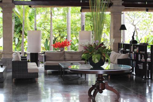 a lobby with couches and a table with flowers on it at Bali Agung Village - CHSE Certified in Seminyak