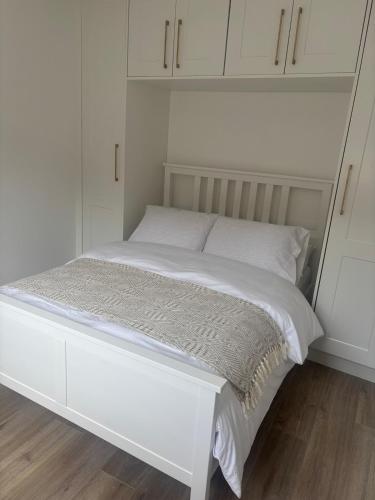 a white bed in a room with white cabinets at Quarry Cottage in Dublin