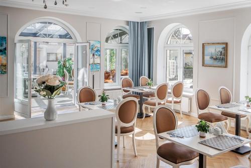 a restaurant with tables and chairs and windows at Moris Beach Hotel in Gdańsk