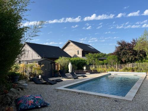 une piscine dans le jardin avec des chaises longues et une maison dans l'établissement Le Gîte du Puit des Granges, à Fontaine-sur-Coole