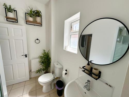 a bathroom with a white toilet and a mirror at Chic & Modern 2BR Apartment - Luxury Manchester Retreat in Manchester