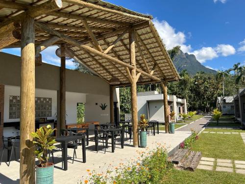a patio with tables and chairs under a pergola at Vila do Porto Pousada in Morretes