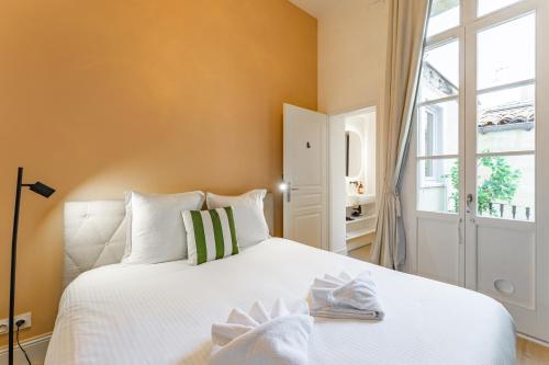 une chambre avec un lit blanc et une fenêtre dans l'établissement Appartement Place Pey Berland avec balcon et parking, à Bordeaux