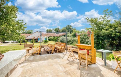 eine Terrasse mit Holzstühlen und Tischen und Bäumen in der Unterkunft Charmante Maison À La Campagne in Bourg-du-Bost
