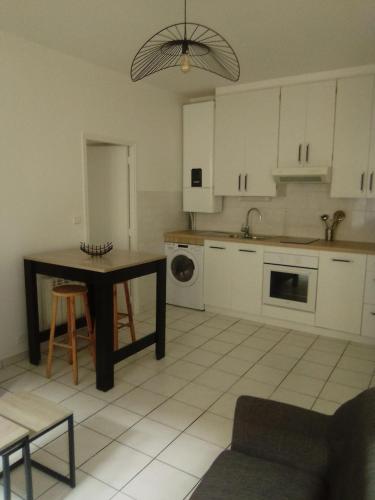 une cuisine avec des armoires blanches, une table et un évier dans l'établissement Appartement moderne à Rodez de 46 m² avec balcon, à Rodez