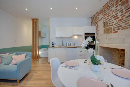 Il dispose d'une cuisine et d'un salon avec une table et des chaises blanches. dans l'établissement Le Grain De Folie / Place Des Halles, à Tours