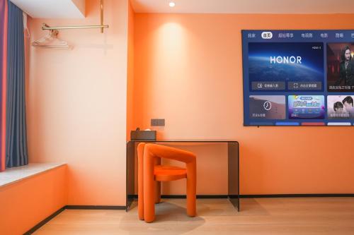 an orange chair sitting next to a table with a screen at Modern Space Hotel-Guangzhou Nansha Wanda Plaza near Line4 STN&Line18 STN in Guangzhou