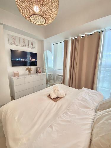 a bedroom with a white bed with a towel on it at Duke & Dahlia Staycation in Sampong