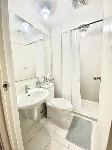 a white bathroom with a toilet and a sink at Duke & Dahlia Staycation in Sampong
