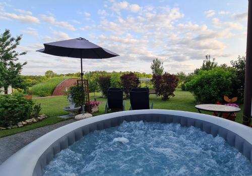 a hot tub with an umbrella in a yard at Domek na wsi z Jacuzzi in Jedle