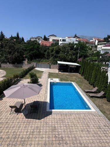 a swimming pool with an umbrella and a table at SUNNY BAY Utjeha in Utjeha
