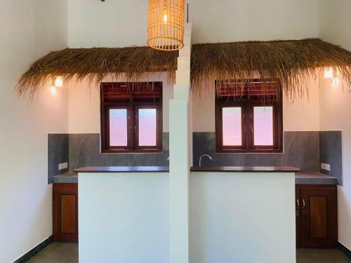 two windows with thatched roofs in a room at Sunray Village Dalawella in Unawatuna