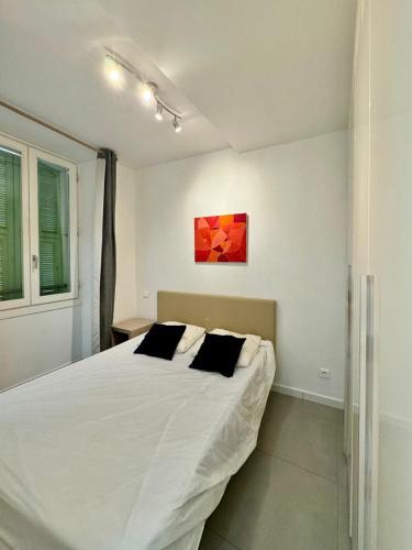 une chambre avec un lit blanc et un tableau au mur dans l'établissement Vieux Nice - Wifi, AC, 6pers, à La Celle-sous-Gouzon