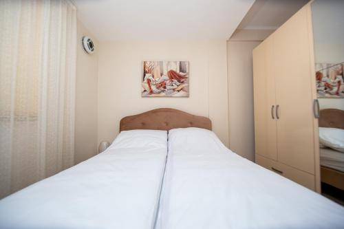 Una cama blanca en una habitación pequeña con cuadros en la pared. en KlubNika, en Budva