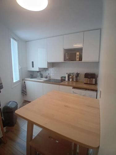 une cuisine avec des armoires blanches et une table en bois dans l'établissement Appartement centre-ville, à Bayonne