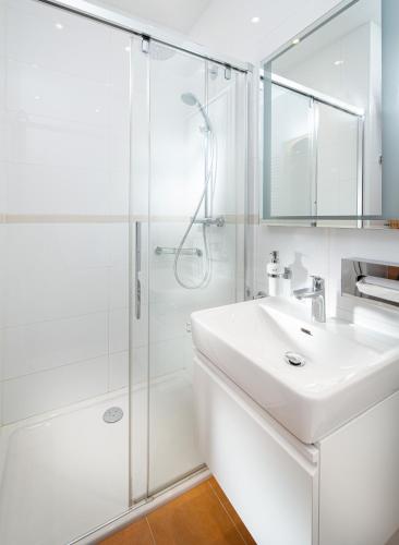 a white bathroom with a sink and a shower at Hotel Höhlenstein in Tux