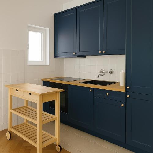 a kitchen with blue cabinets and a wooden table at Mala Kuća in Hodilje