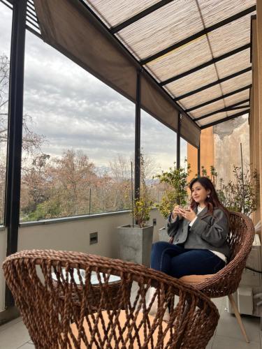 a woman sitting in a wicker chair on a balcony at BHB Hotel Boutique in Santiago