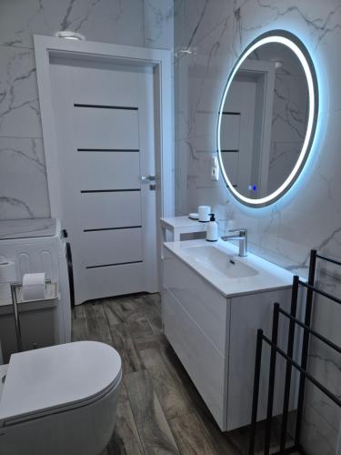 biała łazienka z umywalką i lustrem w obiekcie Brickstone Apartments Mabork w mieście Malbork