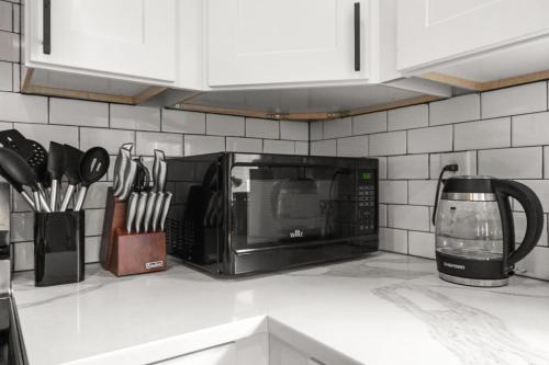 a microwave oven on a kitchen counter with utensils at Boho 5BR Modern Villa w Hot Tub, Grill, Patio and Backyard in Raleigh